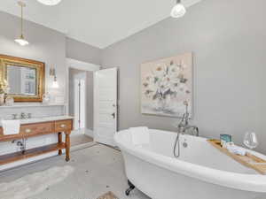 This elegant four-piece bathroom boasts a large, original clawfoot soaking tub, marble tile, and high-end plumbing fixtures. A walk-in shower and a stunning vanity complete the space, while stained glass windows fill the room with colorful light; creating