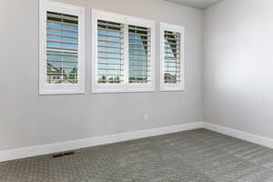 Carpeted spare room featuring baseboards