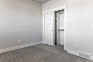 Unfurnished bedroom featuring dark carpet, baseboards, and a closet