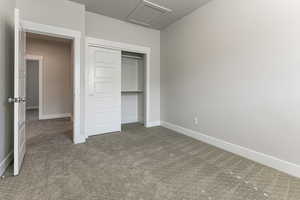 Unfurnished bedroom featuring attic access, carpet, baseboards, and a closet