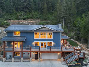 Back of house with a wooded view, covered porch, an attached garage, and metal roof