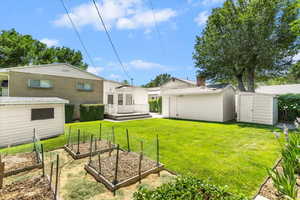 View of green lawn featuring a vegetable garden and a deck