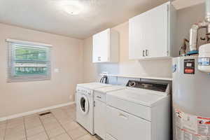 Laundry room featuring gas water heater, washer and dryer, cabinet space, baseboards, and a textured ceiling