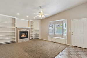 Unfurnished living room featuring recessed lighting, a tile fireplace, a ceiling fan, and baseboards