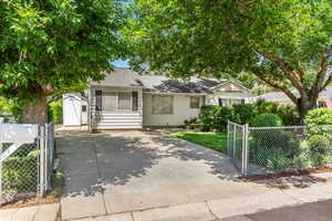 View of front of property with a gate, driveway, a shed, and a shingled roof