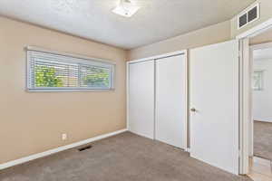 Unfurnished bedroom with carpet floors, a closet, a textured ceiling, and baseboards