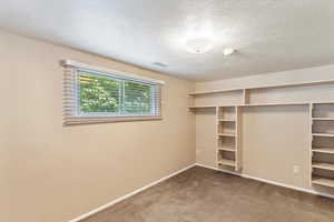 Unfurnished bedroom with carpet, baseboards, a textured ceiling, and a closet