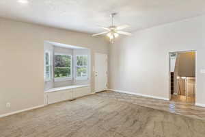 Empty room with a ceiling fan, light tile patterned flooring, baseboards, and light carpet