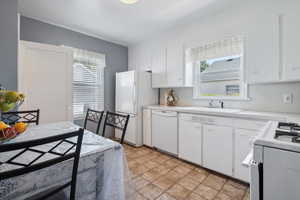 Kitchen featuring white appliances, a sink, light countertops, and white cabinets