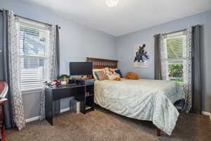 Carpeted bedroom with multiple windows and baseboards