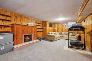 Carpeted living room with wood walls and a brick fireplace