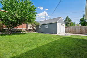 View of yard with a detached garage, an outbuilding, and driveway