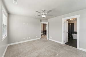 Carpeted empty room with a chandelier, baseboards, and a ceiling fan