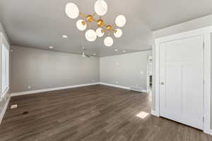 Unfurnished room featuring dark wood finished floors, baseboards, a chandelier, recessed lighting, and a ceiling fan