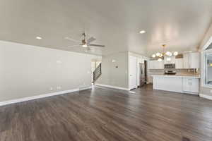 Unfurnished living room with a chandelier, stairway, baseboards, dark wood finished floors, and recessed lighting