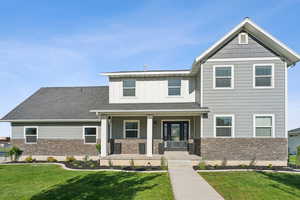 Craftsman-style home with a porch, stone siding, and a front lawn