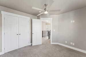 Unfurnished bedroom with carpet, baseboards, a closet, and a ceiling fan