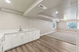 Bar area with a sink, baseboards, light wood finished floors, and recessed lighting