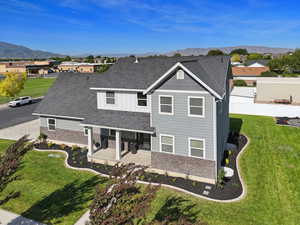 View of front of house featuring stone siding, a mountain view, a patio, and a shingled roof