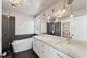Bathroom featuring tile patterned floors, a freestanding bath, double vanity, a stall shower, and tile walls
