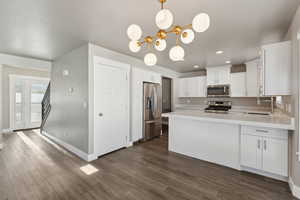Kitchen featuring stainless steel appliances, a sink, light countertops, dark wood-type flooring, and recessed lighting