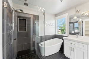 Full bath with a stall shower, vanity, tile patterned flooring, and a freestanding tub