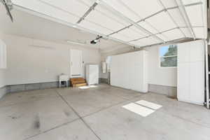 Garage with freestanding refrigerator, a garage door opener, and a sink
