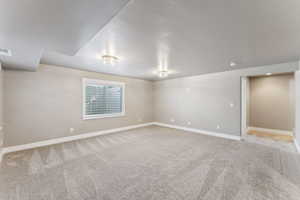 Spare room featuring light colored carpet and baseboards