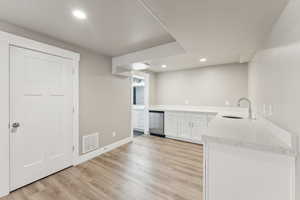 Indoor wet bar featuring light wood-style floors, recessed lighting, baseboards, and dishwasher
