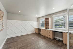 Unfurnished office featuring built in desk, dark wood finished floors, baseboards, and recessed lighting