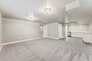 Unfurnished living room with light colored carpet, baseboards, and wet bar