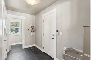 Entryway with dark tile patterned flooring and baseboards