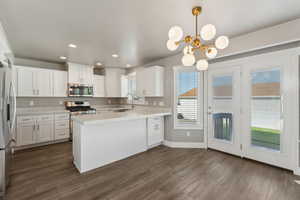 Kitchen with appliances with stainless steel finishes, light countertops, a peninsula, white cabinets, and recessed lighting