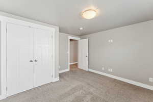 Unfurnished bedroom with carpet flooring, baseboards, and a closet