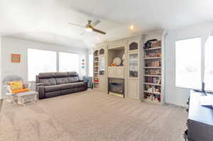 Living room featuring ceiling fan, a glass covered fireplace, carpet, and healthy amount of natural light