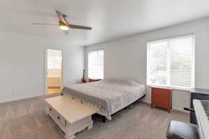 Bedroom featuring carpet, baseboards, a ceiling fan, and ensuite bath