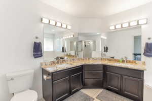 Bathroom featuring a stall shower, double vanity, tile patterned floors, toilet, and a garden tub