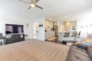 Living room with arched walkways, recessed lighting, a ceiling fan, and dark carpet