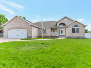 Ranch-style home featuring a garage, brick siding, driveway, and a gate