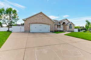 Single story home featuring a gate, brick siding, concrete driveway, and a garage