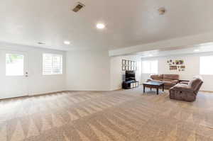 Carpeted living area featuring recessed lighting, plenty of natural light, and baseboards