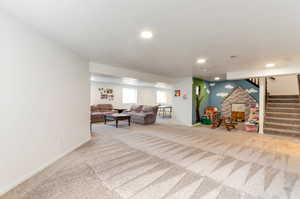 Carpeted living area featuring stairs, baseboards, and recessed lighting