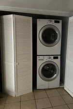 Laundry featuring stacked washer and dryer and light tile floor