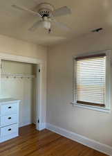 Bedroom featuring closet built-in. wood finished floors, and ceiling fan