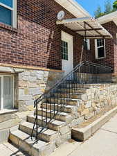 Side entrance to property featuring stone stairs, stone siding, and brick siding