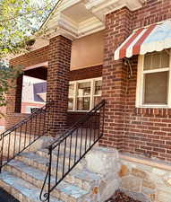 Property entrance with stone stairs, brick siding and porch