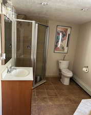 Full bathroom featuring baseboards, vanity, a textured ceiling, a shower stall, jetted tub,and toilet
