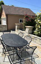 View of stone patio/terrace with outdoor dining space and a garage