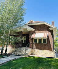 View of front of property featuring brick siding, a chimney, and a front lawn