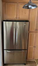 Kitchen view of freestanding refrigerator and maple cabinets